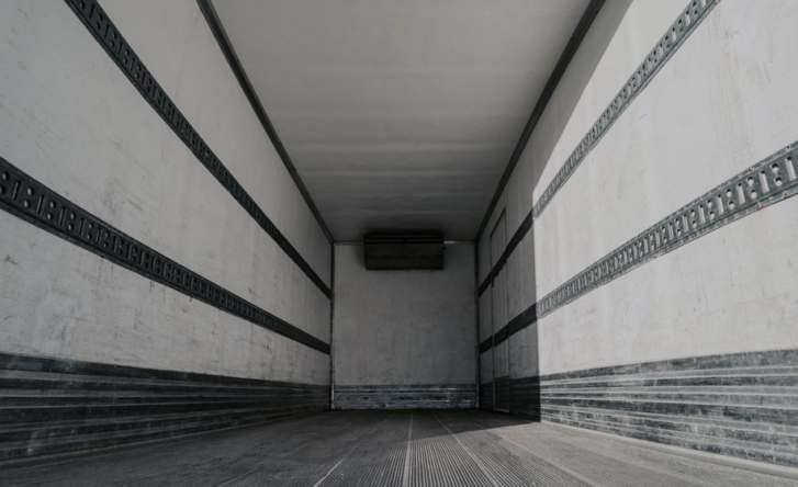 A photo of the inside of an empty cargo truck, with white walls and a black floor.