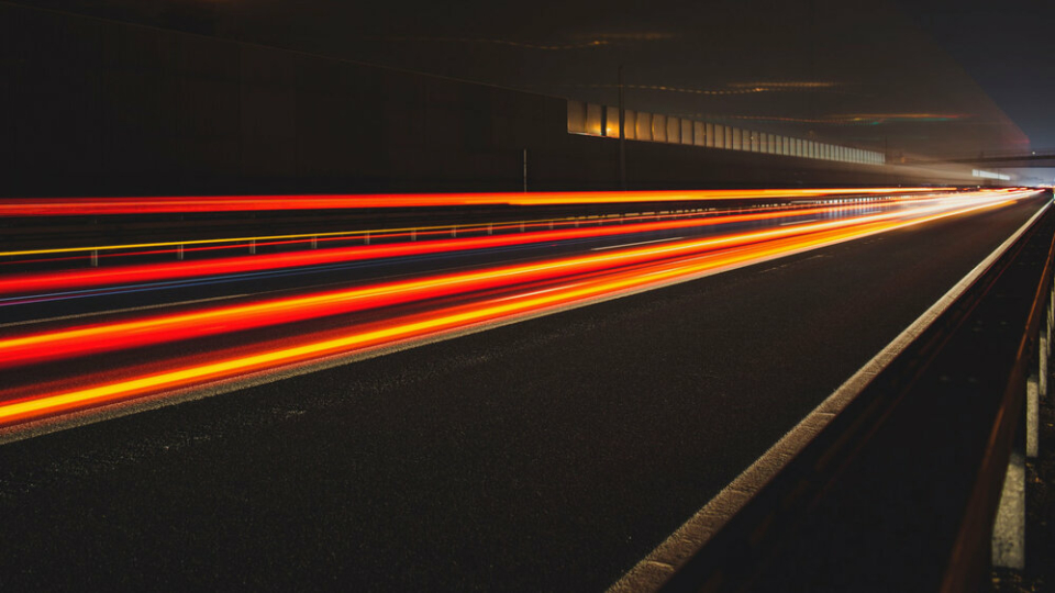 A long exposure shot of traffic through a tunnel, the lights are orange and red streaks.
