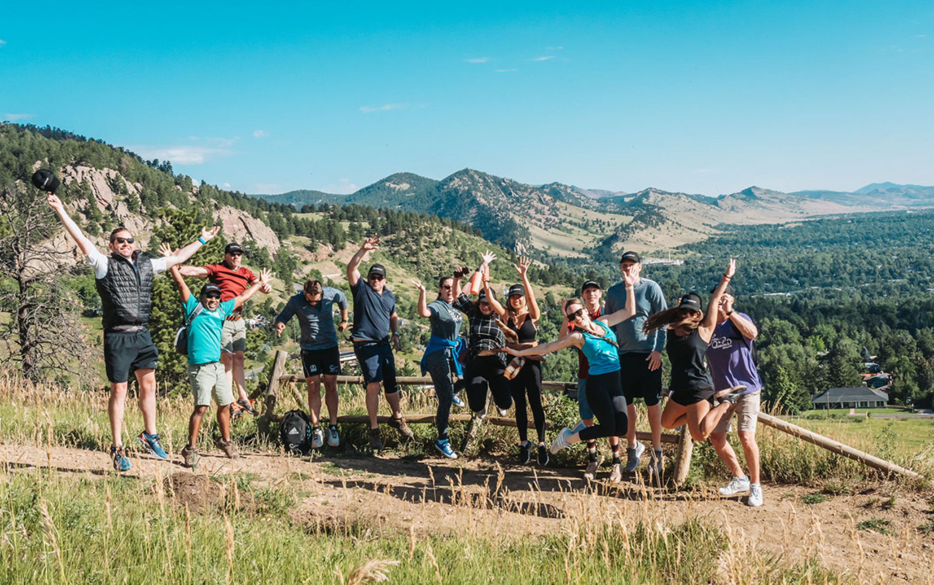 A group shot of the Loadsure team out on a hike in the mountains. Everyone is wearing hiking gear and jumping happily for the photo.