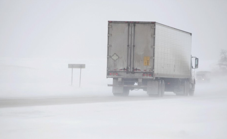 A photo of cargo struck driving through misty snow on a road in winter.