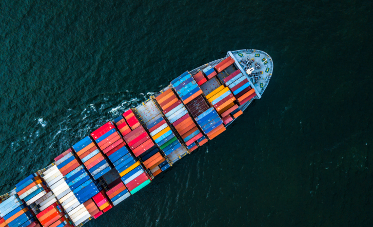 A photo from above of a marine cargo ship in the sea, with many different colour shipping containers on it