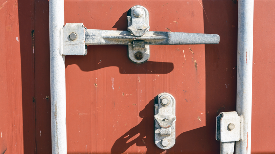 A close-up of the white locking mechanism on a red shipping container.